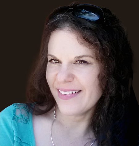 Sari Lisa Armington, smiling, with sunglasses pushed up in her dark curly hair.